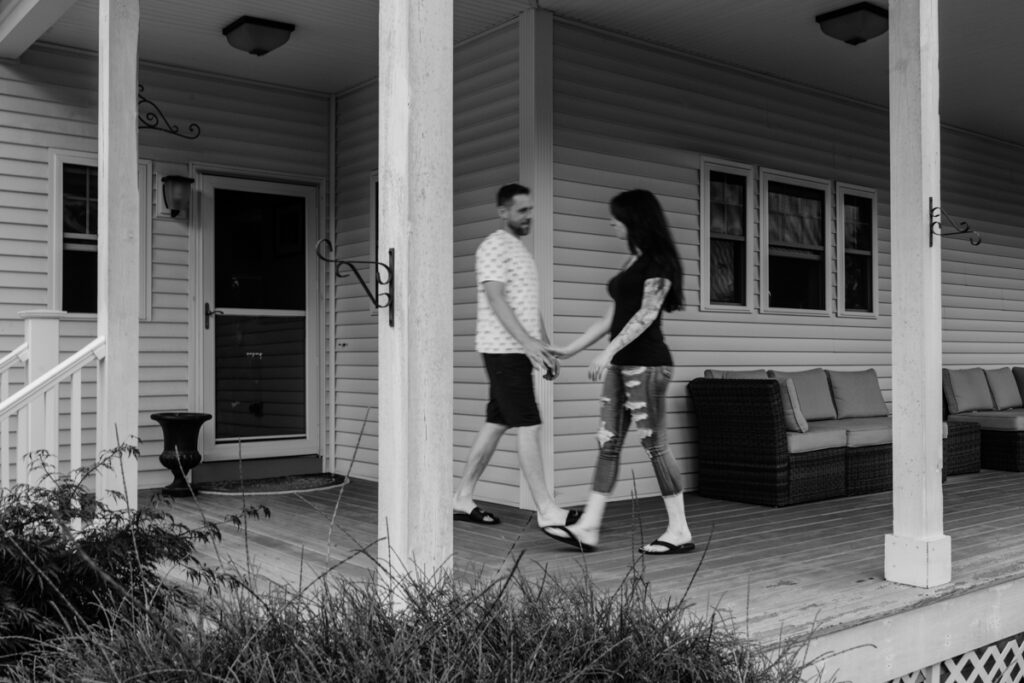 Black and white image of man and woman walking past each other holding hands. The subjects are blurry. 