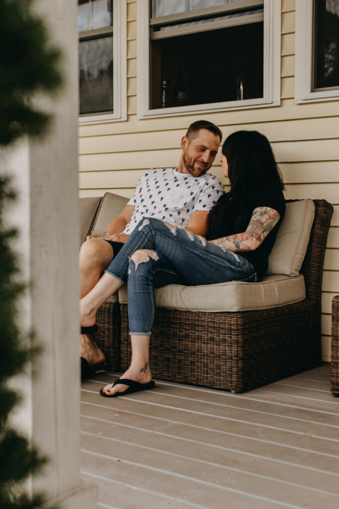 Man and woman sitting on front porch looking at each other for in home photography session 