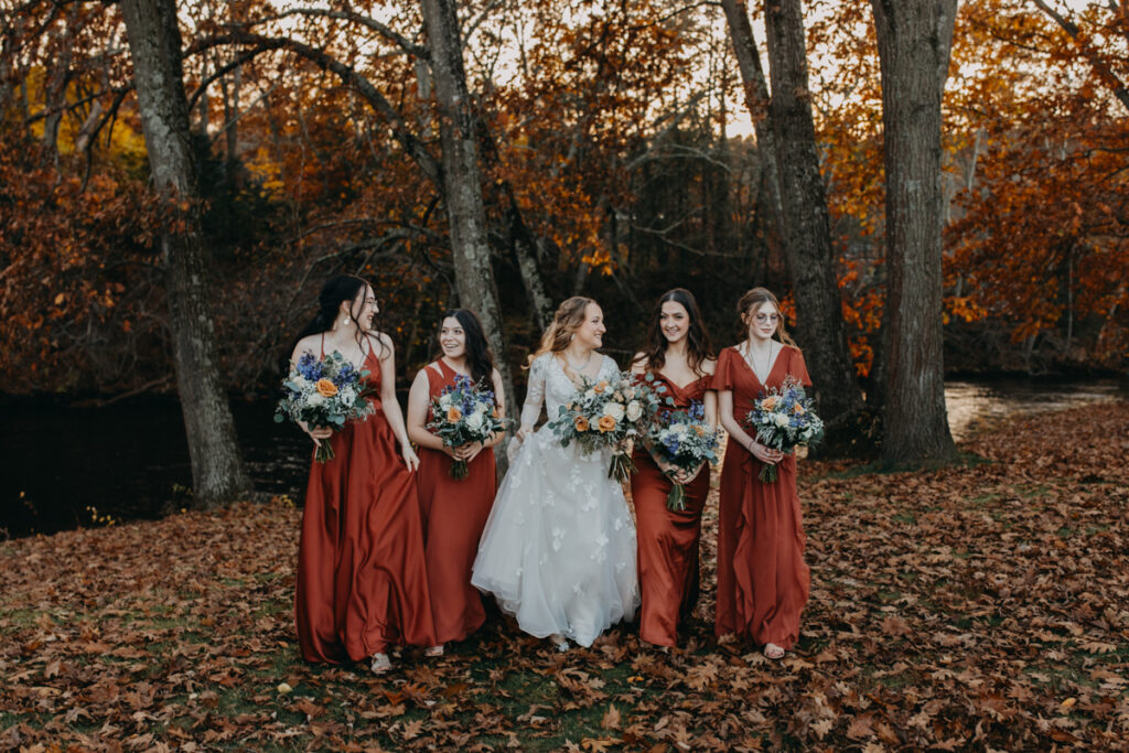 Bridesmaids standing in a line with the bride and walking towards the camera Connecticut Fall wedding photography 