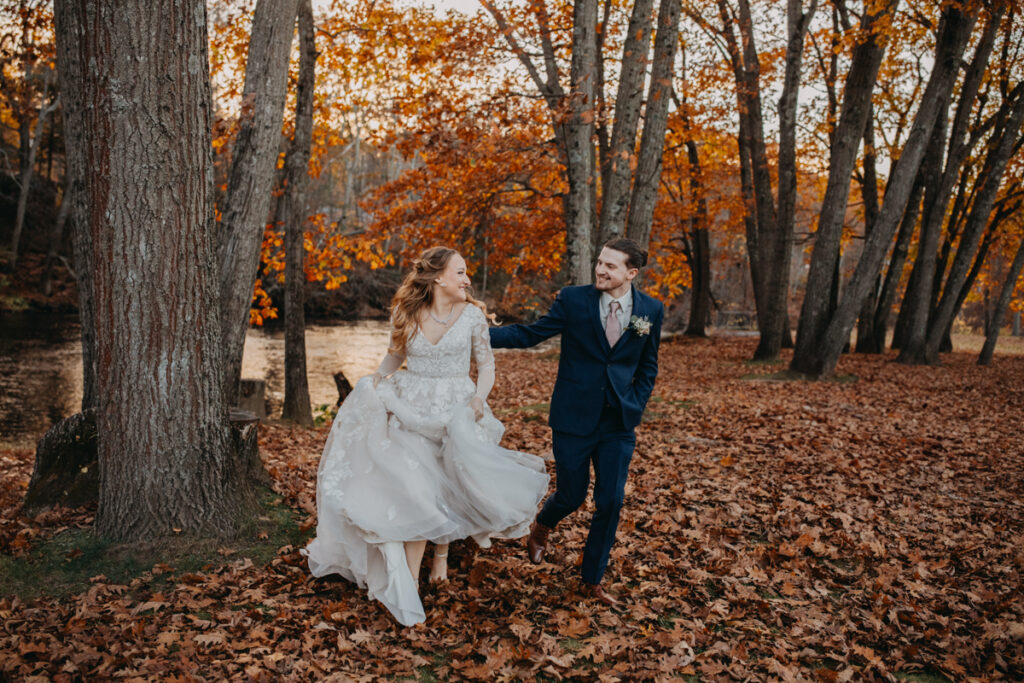 Bride and Groom running in a field with fallen leaves Connecticut Fall wedding photography 