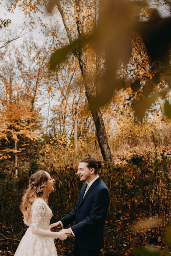Bride and groom facing each other holding hands and laughing Connecticut Fall wedding photography 